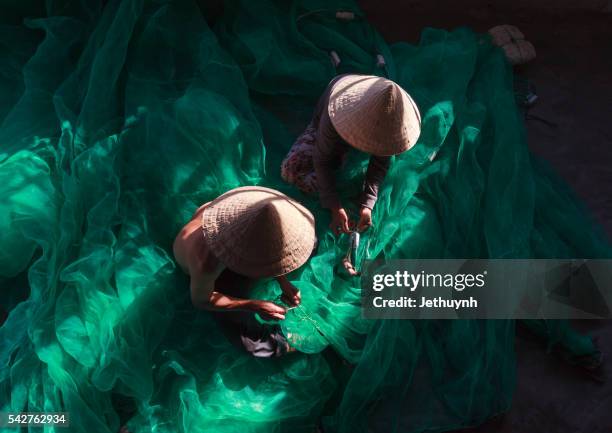 fisherman and women with conical hat in mending fishing net - phan rang stock pictures, royalty-free photos & images