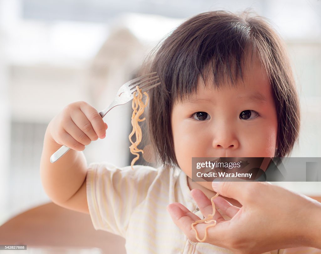 Happy Asian child eating delicious noodle