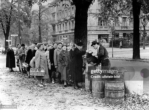 Berliner stehen Schlange, um Kartoffelschalen gegen einen Eimer Brennholz zu tauschen1966