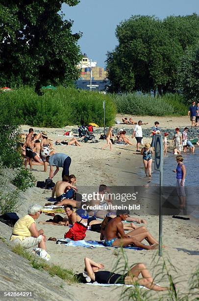 Hamburg: am Elbstrand von Blankenese genießen die Menschen den Sommertag in der Sonne sitzend oder im Wasser stehend.