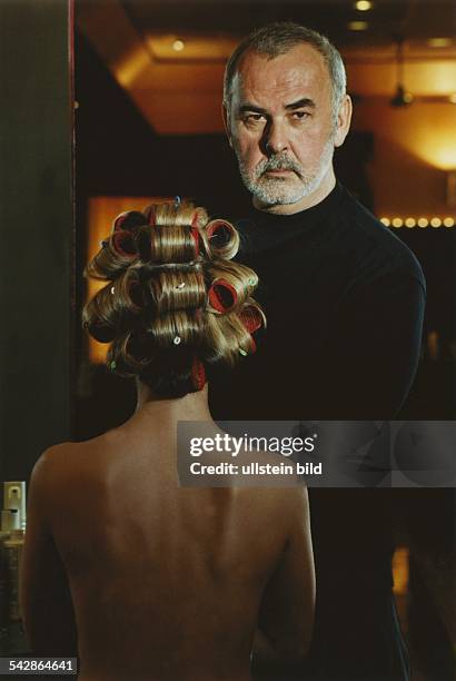 Der Starfriseur Udo Walz in seinem Berliner Salon am Kurfürstendamm. Im Vordergrund eine Kundin mit Lockenwicklern im Haar. Undatiertes Foto.