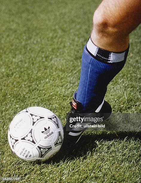 Ein schwarz-weißer Fußball auf dem Rasen. Der Ball trägt den Schriftzug "OFFICIAL BALL OF THE FIFA WORLD CUP 1990" und das Emblem des...