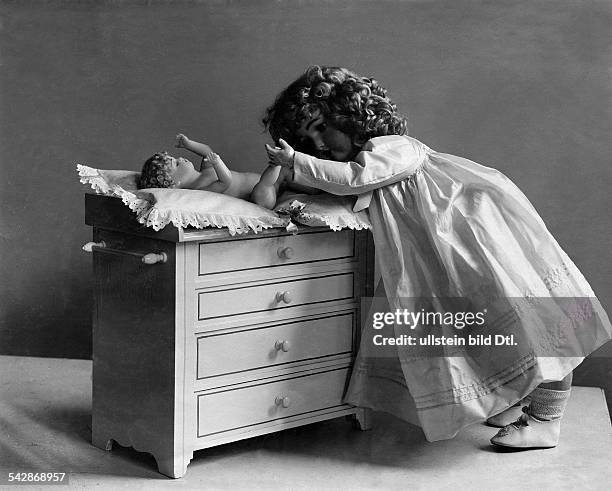 Puppenmutter: eine große Puppe wickelt das Puppenbaby- undatiert, vermutlich 1905