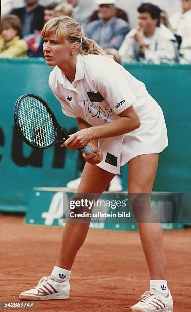 Die deutsche Tennisspielerin Steffi Graf bei den German Open 1990 in Berlin. Sie steht in gebückter Haltung auf dem Sandplatz und erwartet den...