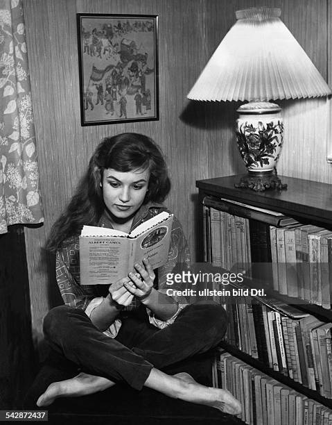 Eine Junge Frau im Schneidersitz liest ein Buch von Albert Camus1950er Jahre