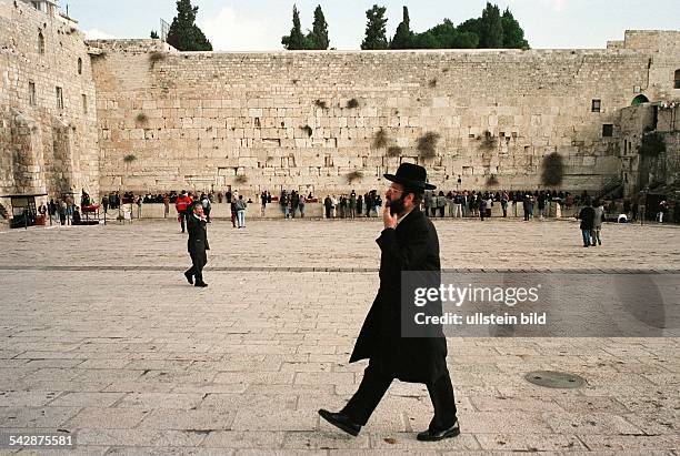 Ein orthodoxer Jude passiert in traditioneller Kleidung - dunkler Mantel und Hut - den Tempelplatz vor der Klagemauer in Jerusalem. Im Hintergrund...