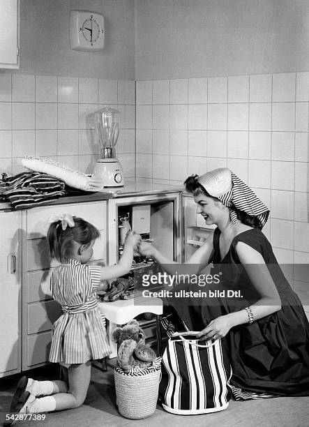 Hausfrau und kleine Tochter füllen einenKühlschrank der Marke AEG Typ 100 auf- 50er Jahre