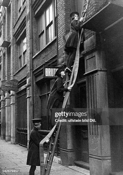 Frauen - Feuerwehr: klettern mit einemFeuerwehrschlauch eine Leiter an einerHauswand hoch- in London 1926