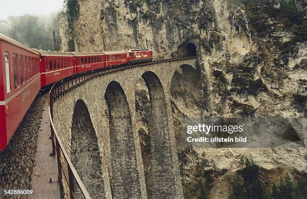 Der Bernina-Expreß der Schweizer Eisenbahn fährt über einen 65 Meter hohen Landwasser-Viadukt in einen Tunnel. Bahn, Brücke, Schweiz, Seilbahn,...