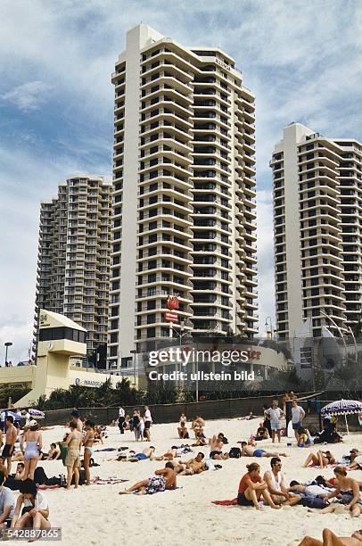 Gold Coast an der australischen Ostküste: Der berühmte Strand von Surfers Paradise vor der Kulisse der Hochhäuser. Menschen sitzen bzw. Liegen im...