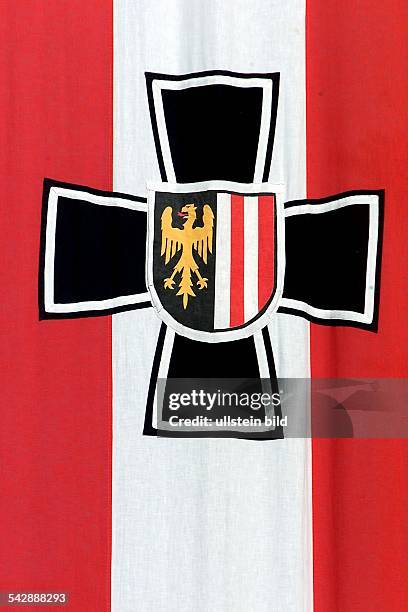 Zeichen des oberösterreichischen Kameradschaftsbundes: auf der Nationalflagge von Österreich: schwarzes Kreuz darauf mittig ein Schild mit Adler und...