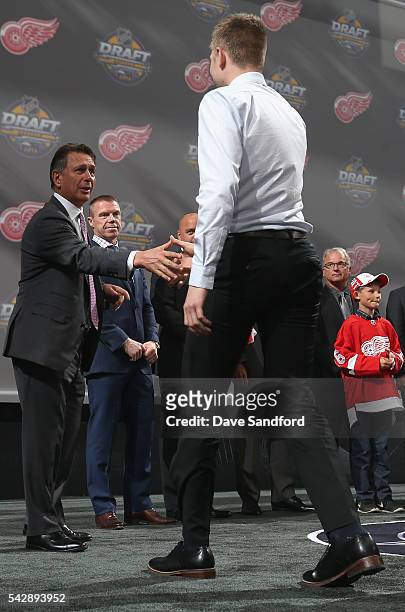 Dennis Cholowski shakes hads with general manager Ken Holland after being selected 20th overall by the Detroit Red Wings during round one of the 2016...