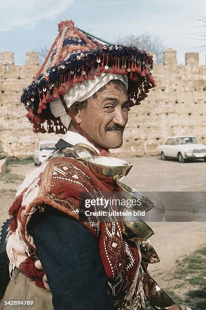 Ein marokkanischer Wasserverkäufer in traditioneller Kleidung, Trinkgefäße an einem Gürtel. Undatiertes Foto, Eingang ins Fotoarchiv 1997.