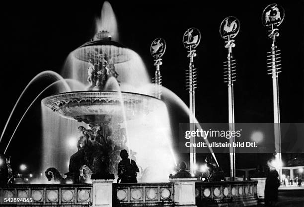 Weltausstellung Paris: Springbrunnen und Eingangstor zur Pariser Weltausstellung auf dem Place de la Concorde im Scheinwerferlicht.Nachtaufnahme- 1937