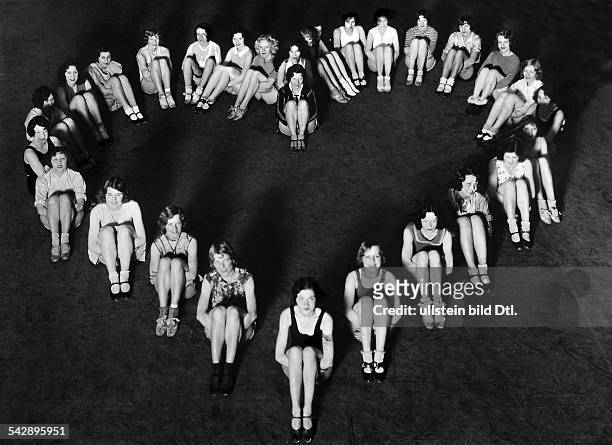 Tanzgirls sitzen auf dem Boden und haben eine Herzform gebildet- 1929