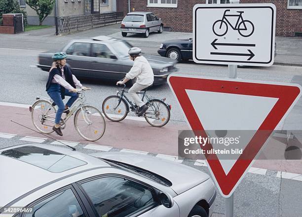 Straßenschild "Vorfahrt beachten" mit Zusatzschild. Das Zusatzschild mit einem abgebildeten Fahrrad und zwei entgegengesetzten Pfeilen darunter weist...