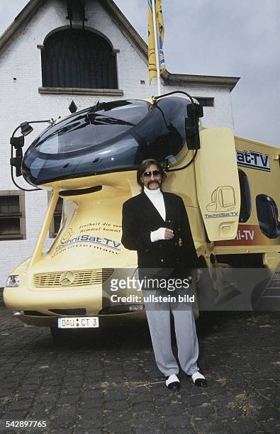Luigi Colani*-Konstrukteur, Designer, Schweizmit verbundenem Arm vor einem von ihm entworfenen Truck , der bei Mercedes in Serie geht. Undatiert