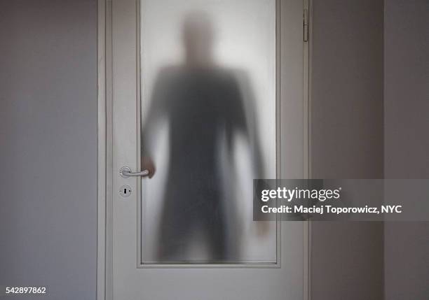 human figure entering room behind translucent doors. - stranger danger stock pictures, royalty-free photos & images