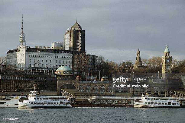 Hamburg: Landungsbrücken mit Altem Elbtunnel und Uhrenturm, davor zwei alte Hadag-Schiffe. Im Hintergrund das Bismarck-Denkmal und das "Hotel Hamburg...