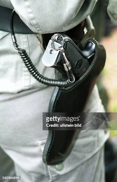 Polizei: Pistole mit Halfter und Diebstahlssicherung am Gürtel eines französischen Polizeibeamten. .
