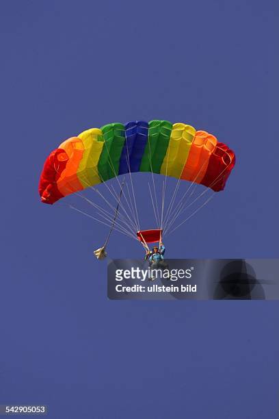 Zwei Menschen an einem bunten Gleitschirm bei blauem Himmel. Paragliding; Tandemspringen; Fallschirmspringen; Gleitschirmfliegen