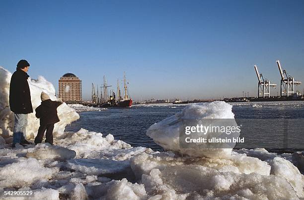 Hamburg: hoch türmen sich die Eisschollen am Elbstrand bei Övelgönne. Am Ufer steht ein Vater mit seinem Kind. Im Hintergrund der Museumshafen und...