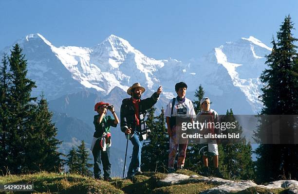 Beatenburg, Berner Oberland, Schweiz: Familie beim Wandern. Im Hintergrund die Schnee bedeckten Gipel von Eiger, Mönch und Jungfrau . .