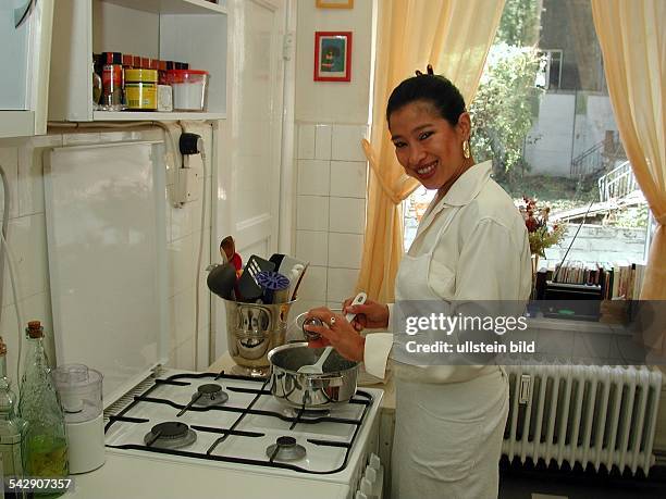 Die Generalkonsulin von Honduras, Patricia Rivera Rodil, beim Kochen an einem Gasherd. Bekleidet mit einer weißen Schürze würzt sie das Gericht in...