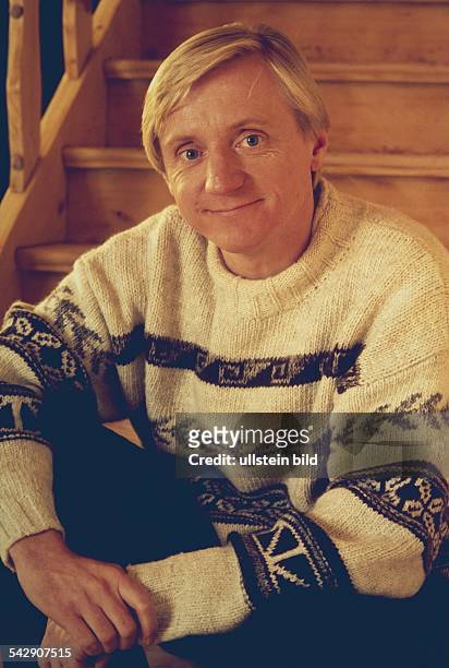 Schauspieler Pierre Franckh, im Rollkragenpullover, sitzt auf einer Holztreppe. Aufgenommen um 1995.
