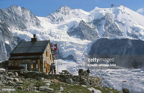 Die schweizerische Flagge ist gehisst vor der Berghütte Cabane d' Ar Pitetta des Schweizer Alpenclubs vor der wilden Kulisse des Mominggletschers ,...
