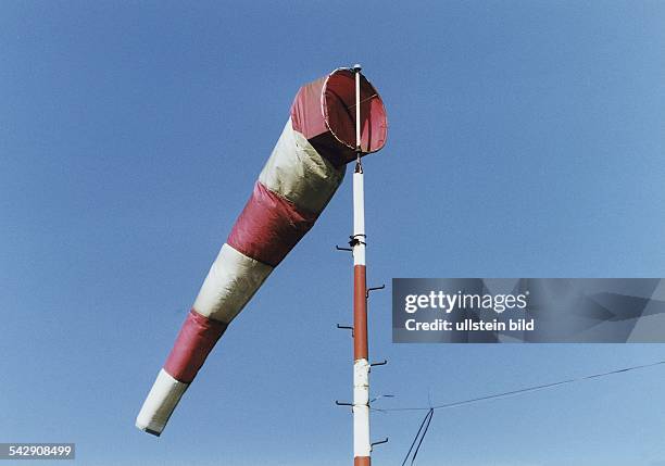 Auf dem Flugplatz Hartenholm hängt ein Windsack an einer Stange. Er ist rot-weiß gestreift und bläst sich leicht mit Wind auf. Aufgenommen August...