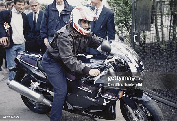 Die argentinische Tennisspielerin Gabriela Sabatini sitzt auf einer 600er Yamaha. Sie trägt eine Lederjacke und einen Motorradhelm. Im Hintergrund...