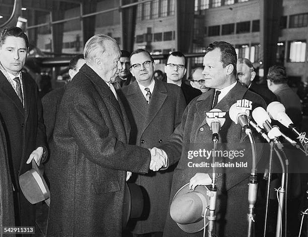 Bundeskanzler Konrad Adenauer und Willy Brandt, der Regierende Bürgermeister von Berlin, schütteln sich 1962 vor den Mikrophonen einiger...