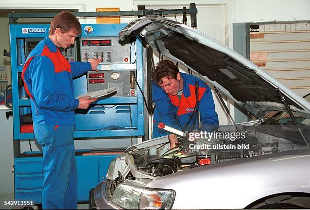 Zwei Automechaniker überprüfen in einer Werkstatt des Autokonzerns Nissan ein Auto. Die Motorhaube des KFZ ist geöffnet. Ein Mechaniker überprüft den...