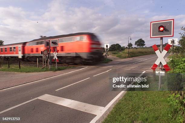 Bahnübergang ohne Schranke in Schulendorf ein. Ein D Zug rast mit Tempo 120 km/h durch den Bahnübergang. Im Vordergrund Lichtsignal und Andreaskreuz....