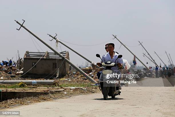 Villagers ride through a damaged road in Danping Village of Chenliang Township on June 25, 2016 in Funing, Yancheng, east China's Jiangsu Province. A...