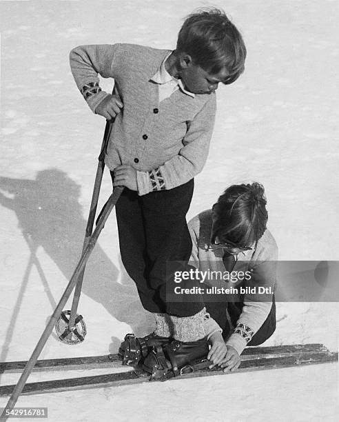 Die neuen Skier werden ausprobiert" - ein Junge hilft einem anderen Jungen beim Befestigen der Skier- 1932/1933Aufnahme: Martin Munkacsy