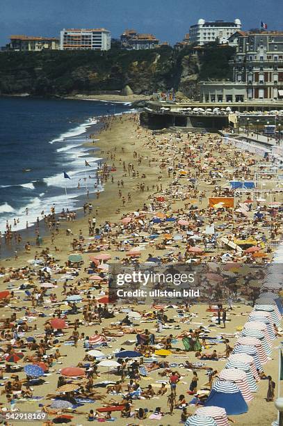 Badevergnügen am Strand des bekannten Seebades Biarritz: Badegäste / Menschen liegen im Sand oder baden im seichten Wasser des Atlantiks. Im...