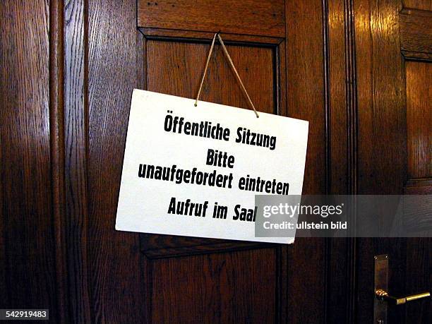 Hinweisschild einer öffentlichen Sitzung an der Tür eines Gerichtssaals im Ziviljustizgebäude. Das Schild trägt den Text "Öffentliche Sitzung, Bitte...