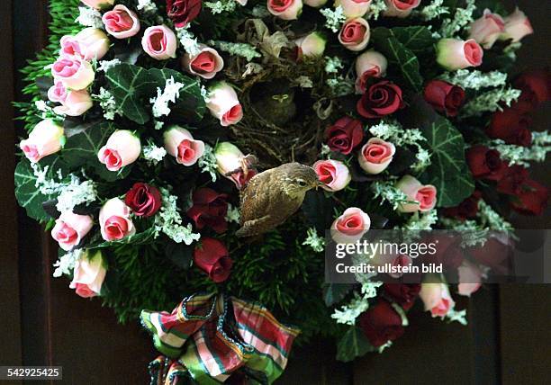 Ungewöhnlicher Nistplatz: Nest eines Zaunkönigs in einem Strauß aus künstlichen Rosen an einer Haustür. .