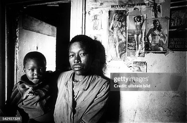 Schwarze Frau mit einem Kind auf dem Arm in einem Wohnghetto südwestlich vom Zentrum von Johannesburg- Juni 1976