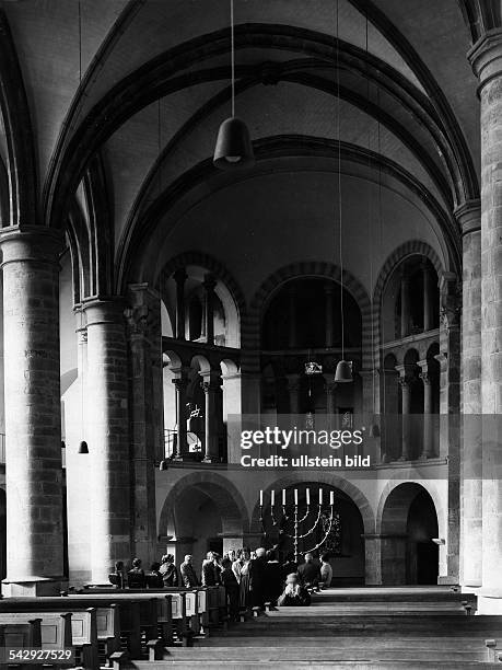 Besuchergruppen vor dem siebenarmigen Leuchter in der Münsterkirche zu Essen. Gestiftet von der Äbtissin Mathilde Bronze, Höhe 2,26m
