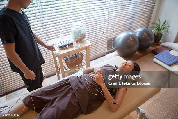 japanese female having acupuncture treatment with expert in kyoto japan - man electric chair stock pictures, royalty-free photos & images