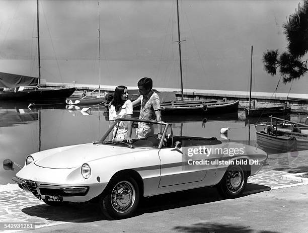 Werbefoto: Mann und Frau an lehnen an einem Alfa Romeo Spider 1300 Junior vor Yachthafen - Kulisse an einem See- Juli 1968