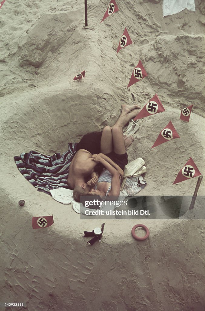 Germany Nazi era. A young German couple in a sandcastle decorated with swastika pennants and banners - Summer 1939 or 1940