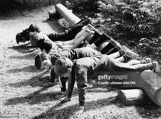 Kinder machen Liegestütze auf einem Trimm-Dich-Pfad im Wald1972