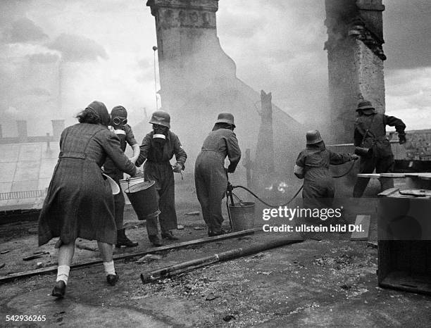 Weltkrieg, Deutsches Reich - Löscharbeiten auf einem Hausdach; vermutlich eine Brandschutzübung;im Vordergrund eine Frau mit Gasmaske und...