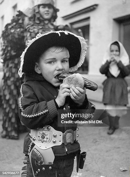 Ein Junge in einem Cowboy - Kostüm ißt eine Rostbratwurst im Brötchen- 1969