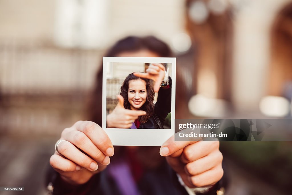 Garota mostrando instantâneo de fotografia de mão do conceito de enquadramento