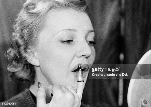 Frau schminkt sich die Lippen mit einem Lippenstift, der die Form eines Fingerhuts hat, USA- 1938